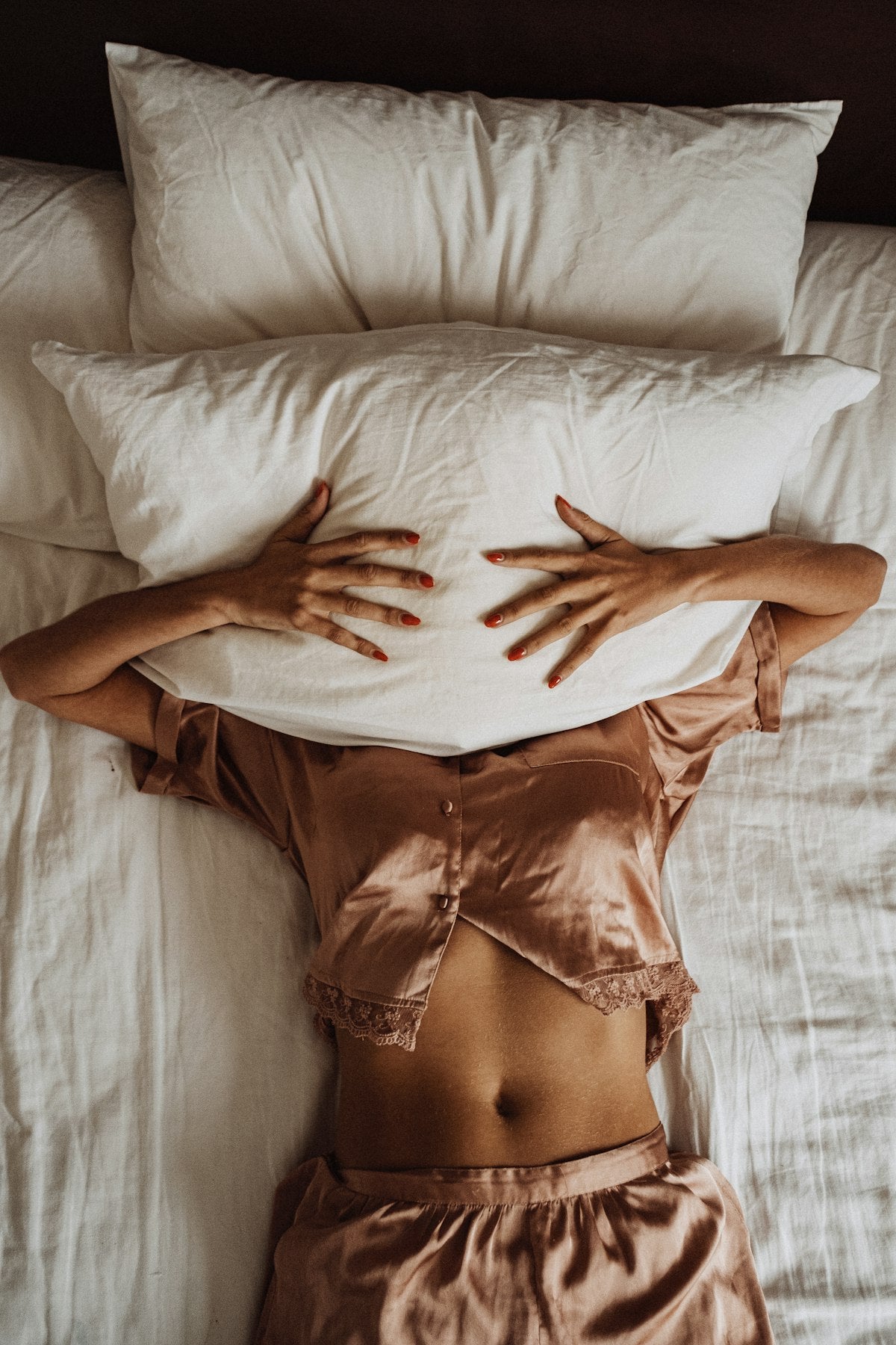 Frau im Bett mit Händen auf Kissen
