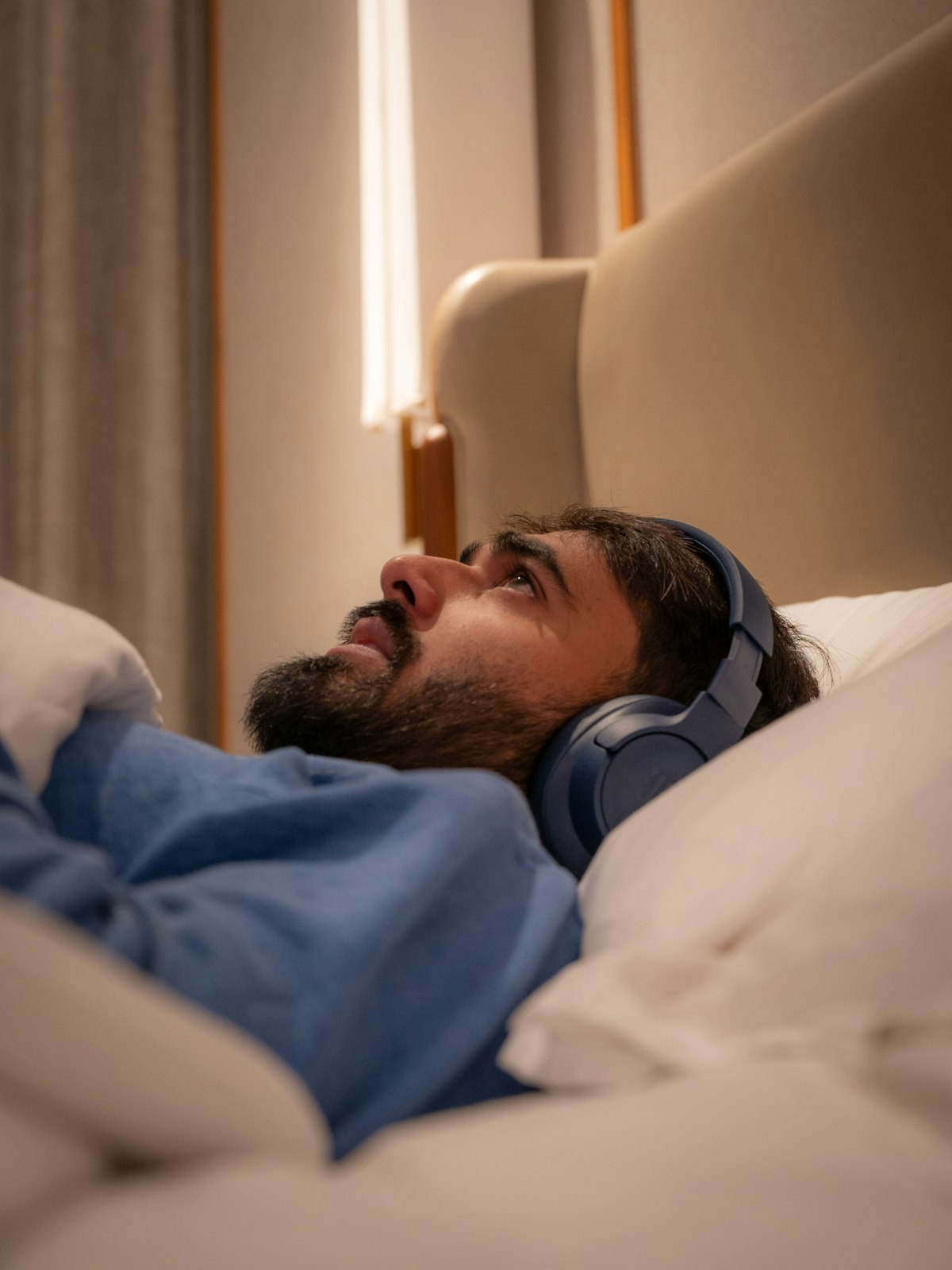 Mann liegt im Bett mit Kopfhörern